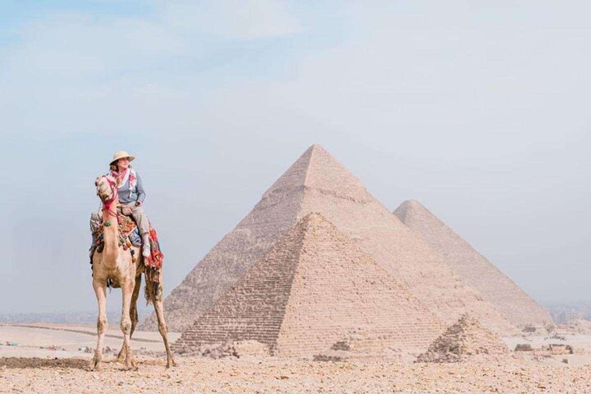 muž jazdiaci na ťave pred pyramídami