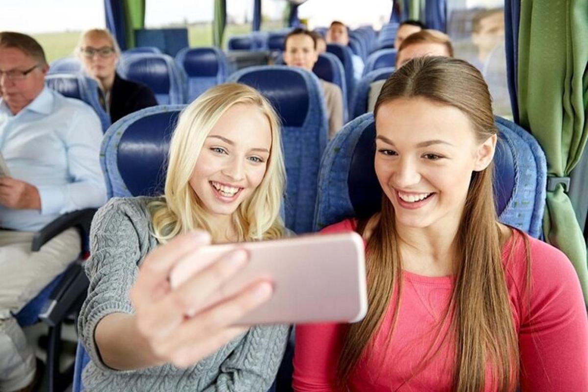 due ragazze sedute su un autobus che guardano un cellulare