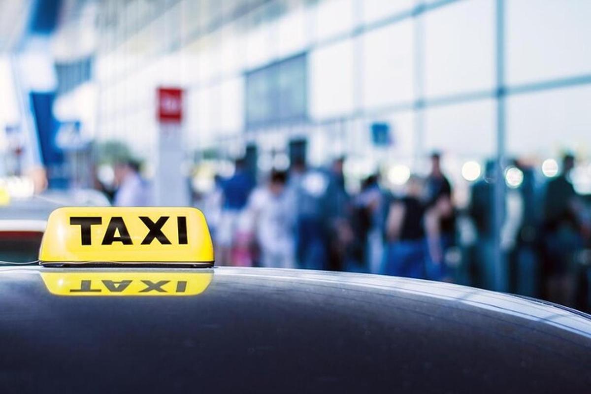Un cartel de taxi amarillo en el capó de un coche.