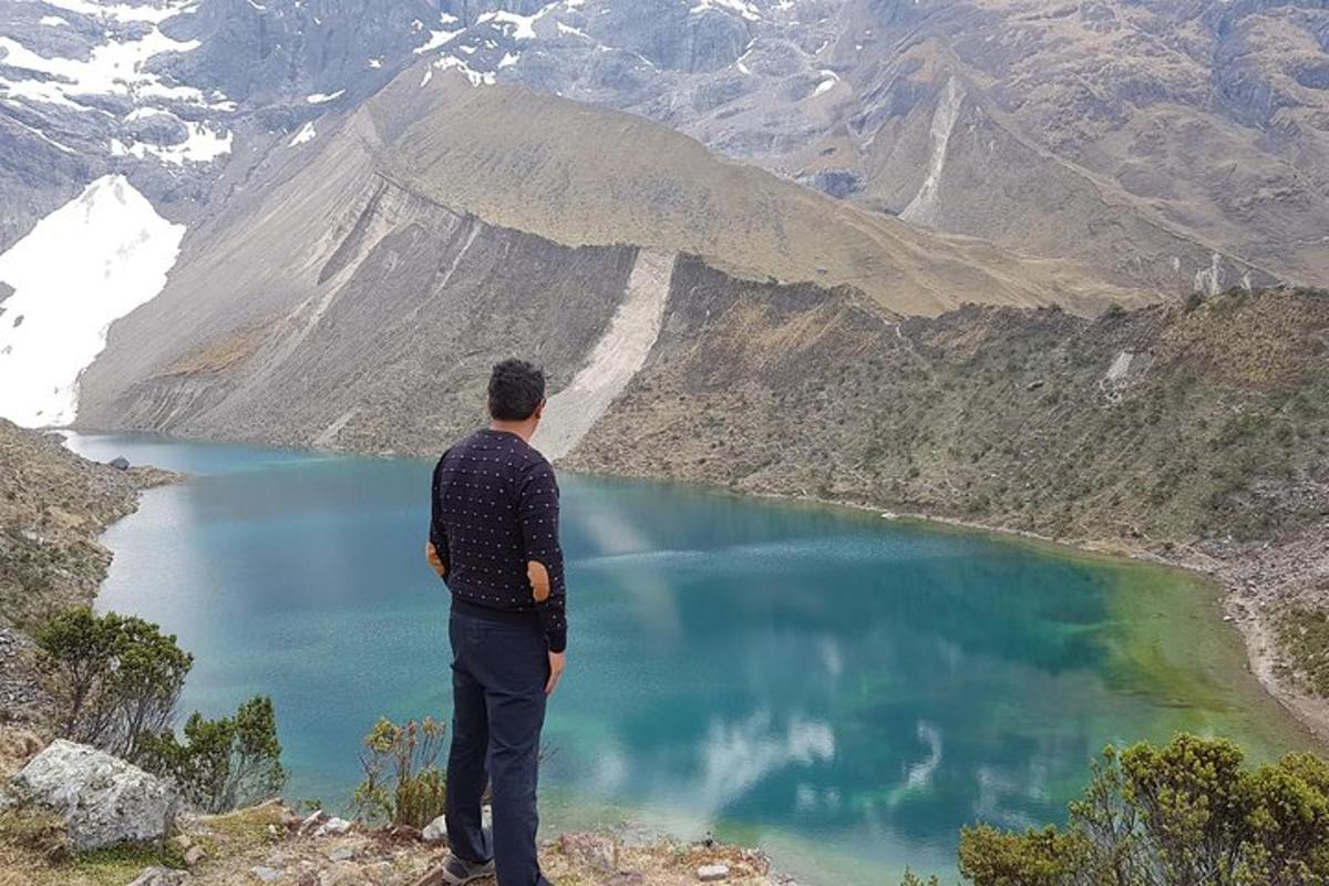 muž stojící na vrcholu hory a dívající se na jezero