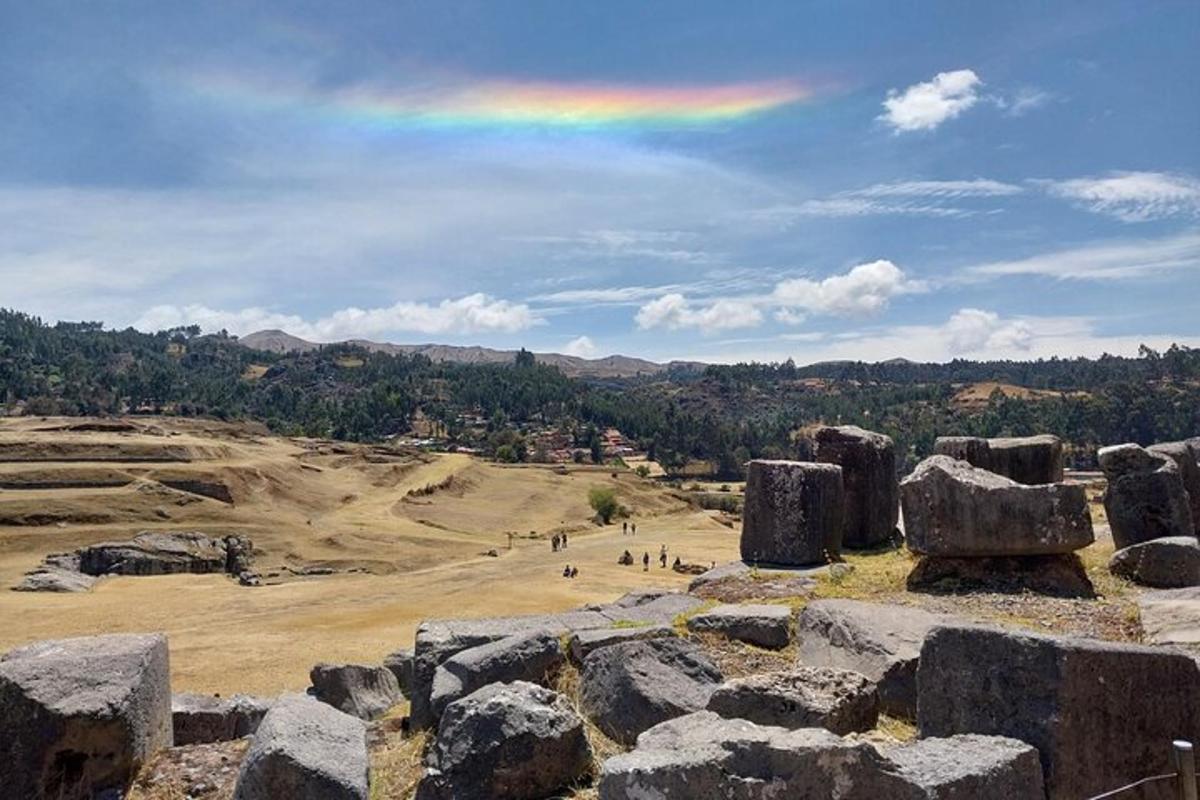 a rainbow in the sky over a field with large rocks