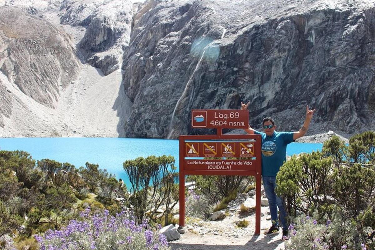 a person standing next to a sign in front of a mountain