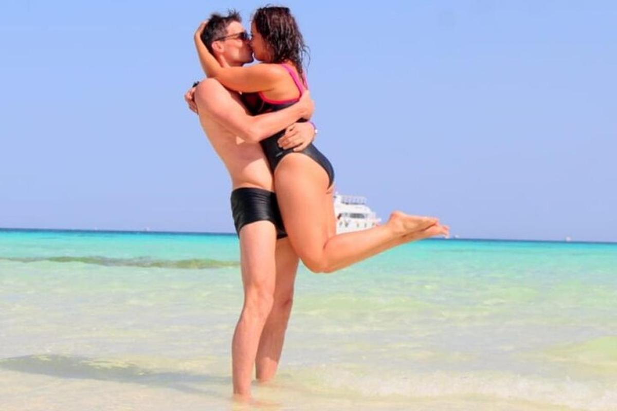 Una mujer abraza a un hombre en la playa.