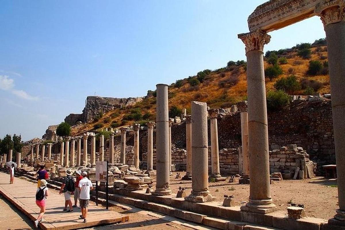 un gruppo di persone che camminano intorno a una fila di colonne