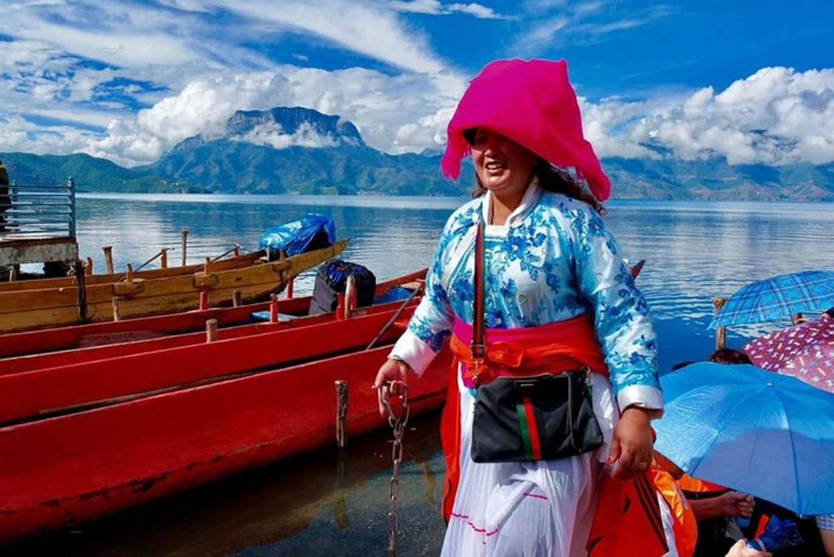 a woman standing next to a red boat in the water