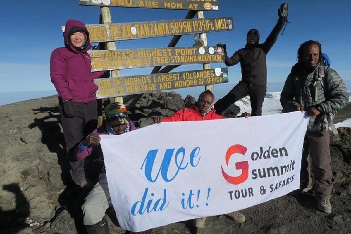 Un grupo de personas sosteniendo un cartel en la cima de una montaña.