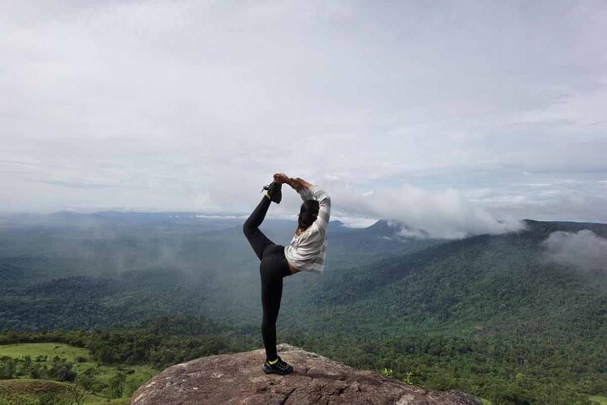eine Frau, die auf einem Berggipfel eine Yoga-Pose macht