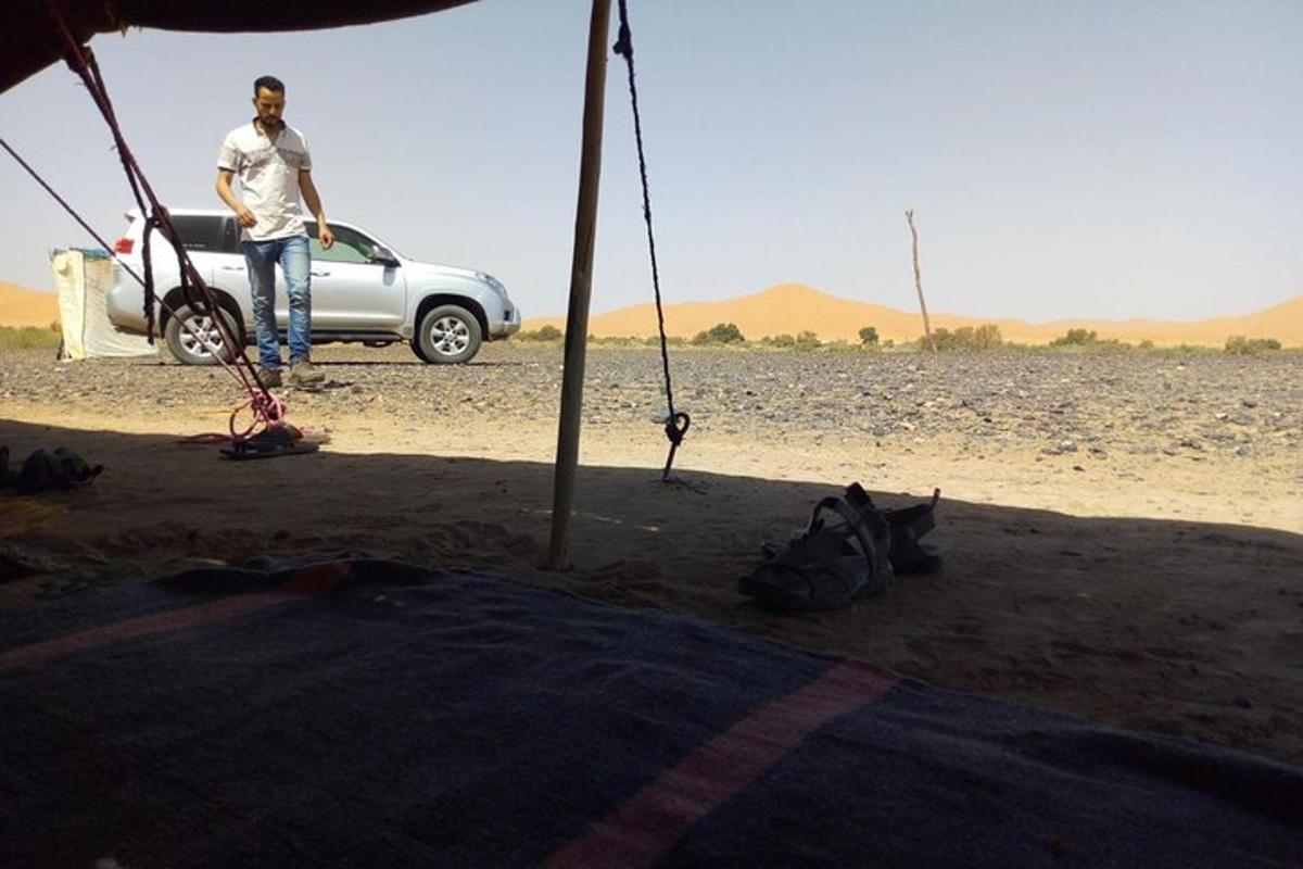 un home dret al costat d'un cotxe al desert