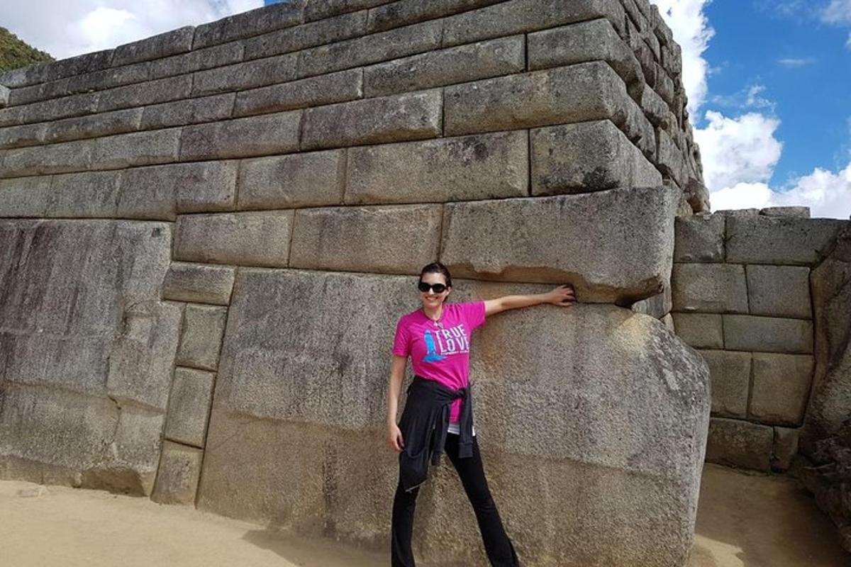 una donna in piedi accanto a un grande muro di pietra
