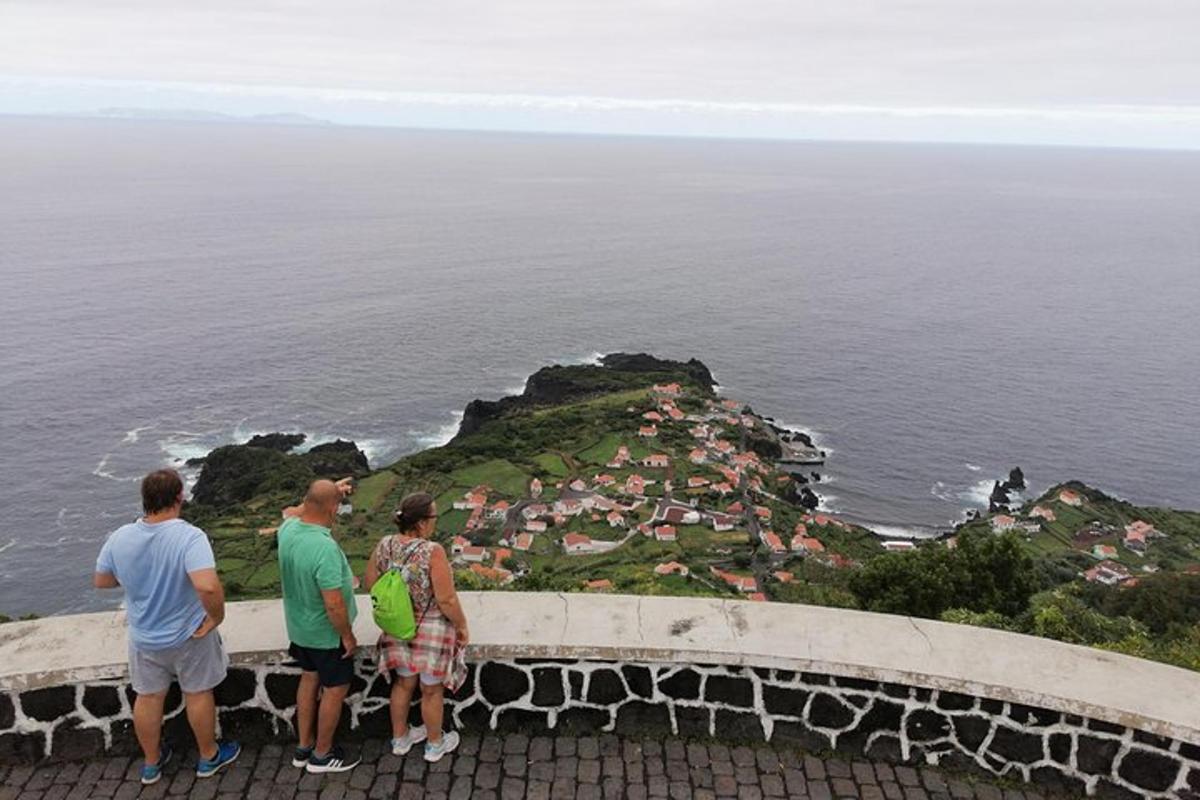 tři lidé stojící na římse a dívající se na oceán