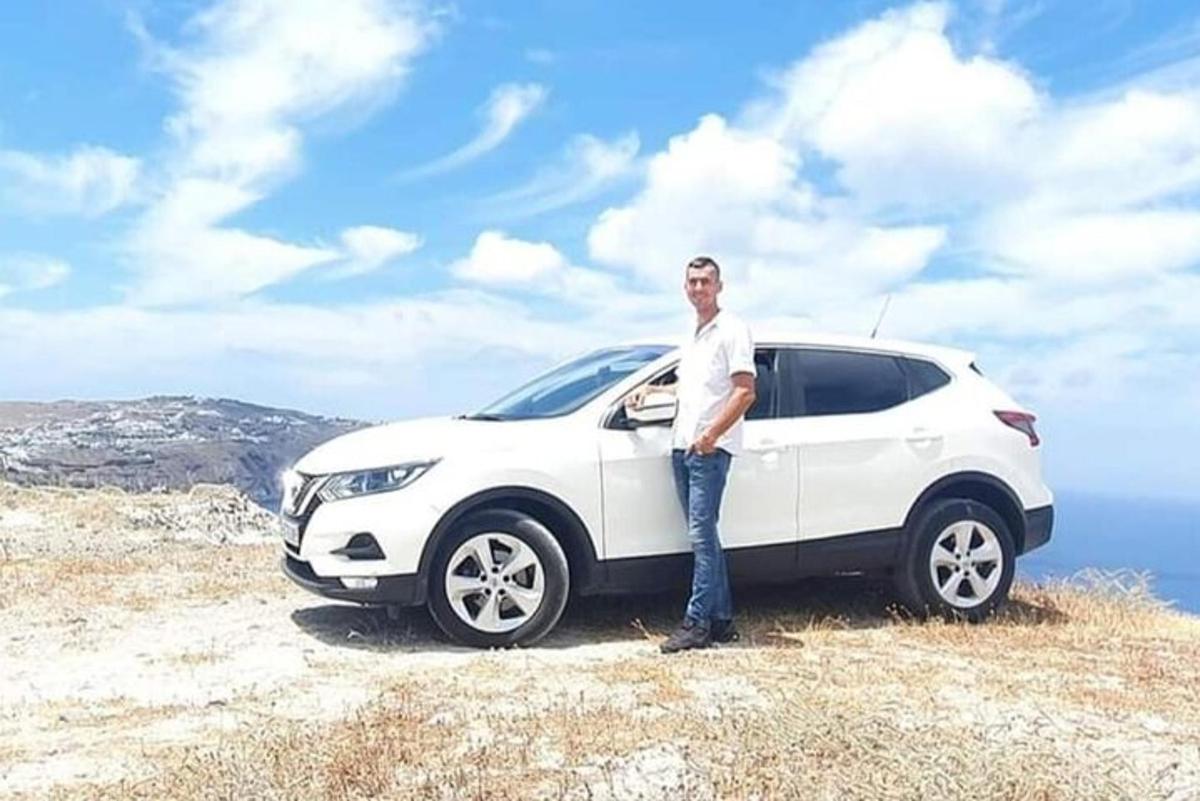 seorang lelaki berdiri di sebelah kereta putih di atas bukit