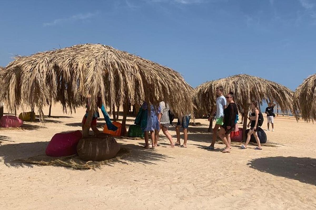 a group of people walking under a straw umbrella on the beach