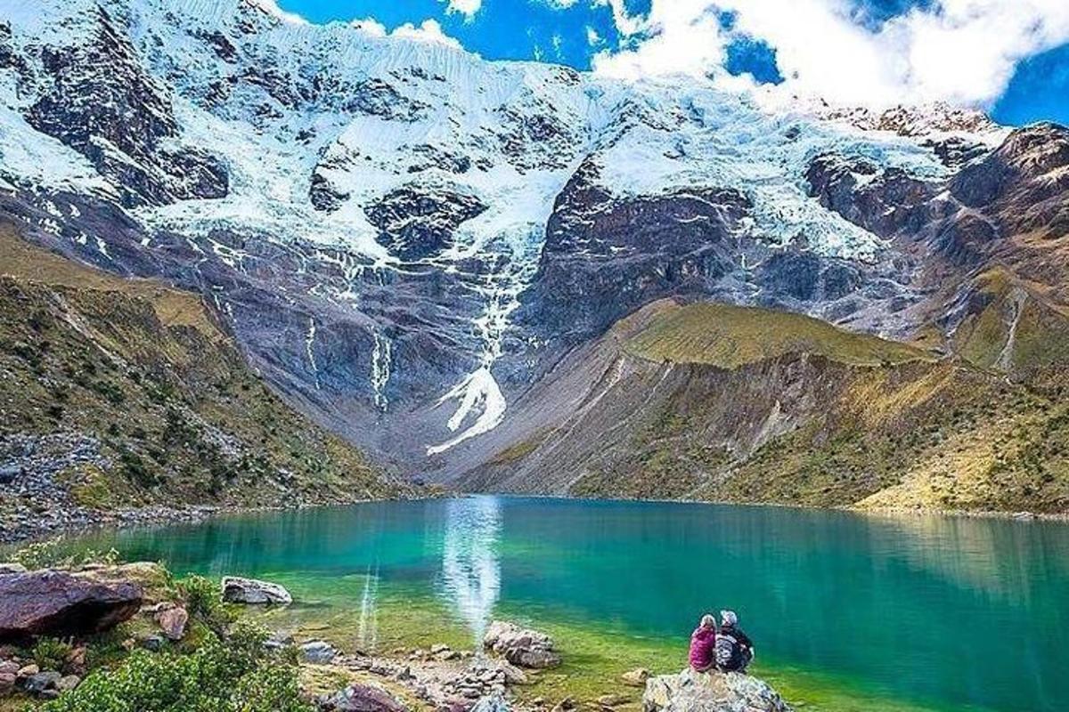 due persone sedute su una roccia vicino a un lago di montagna