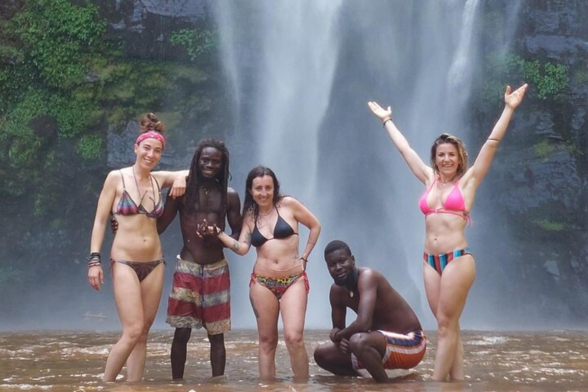 un groupe de femmes debout dans l'eau devant une cascade