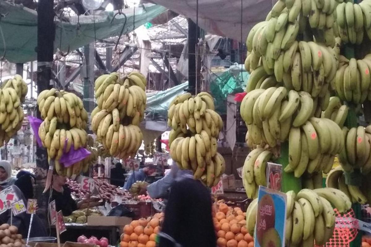 een markt met trossen bananen die aan haken hangen