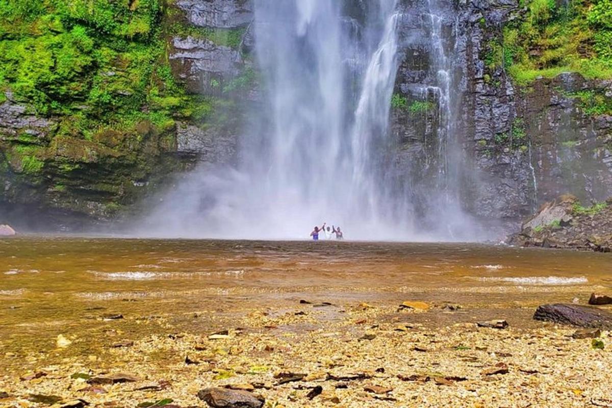 sekumpulan orang berdiri di dalam air di hadapan air terjun