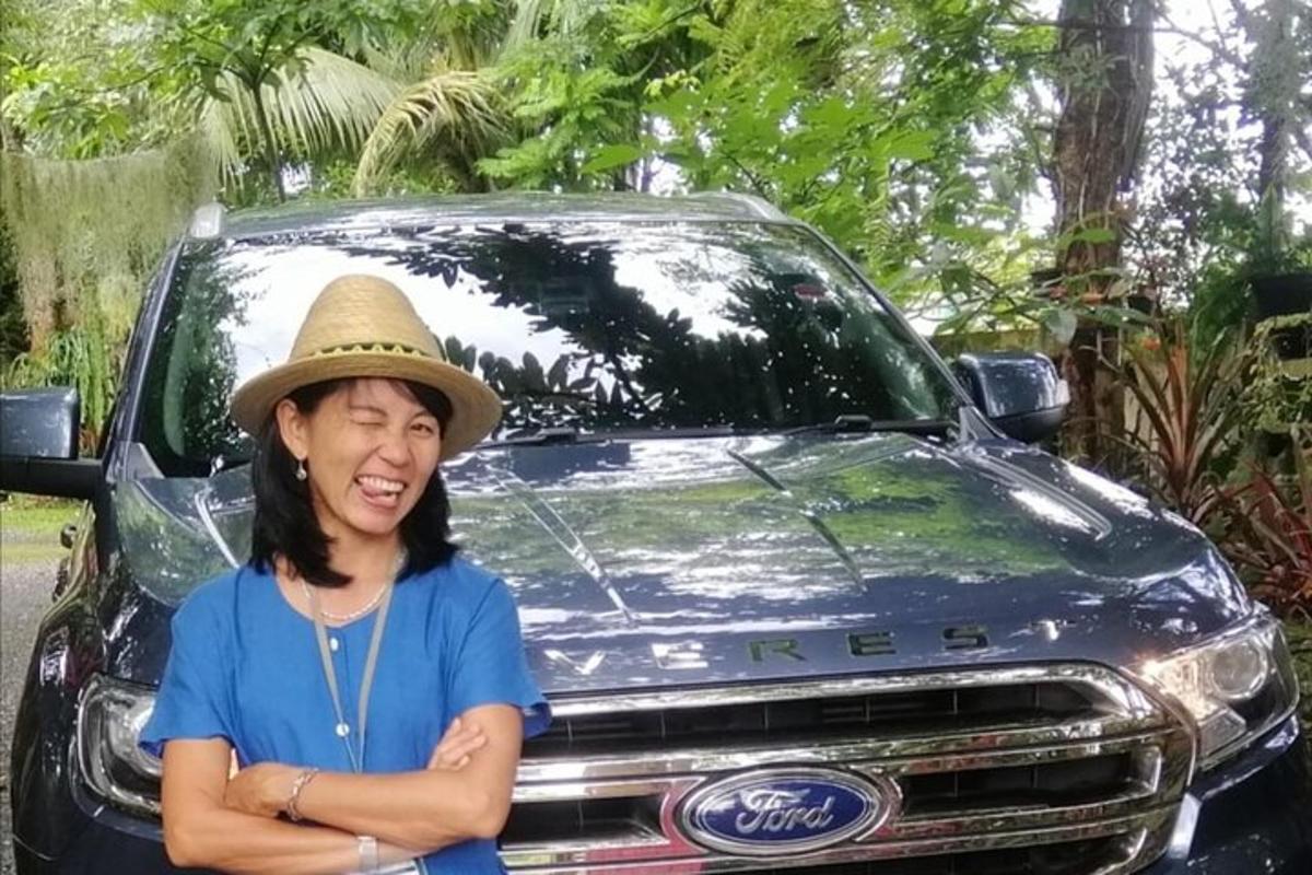 a woman wearing a hat standing in front of a car