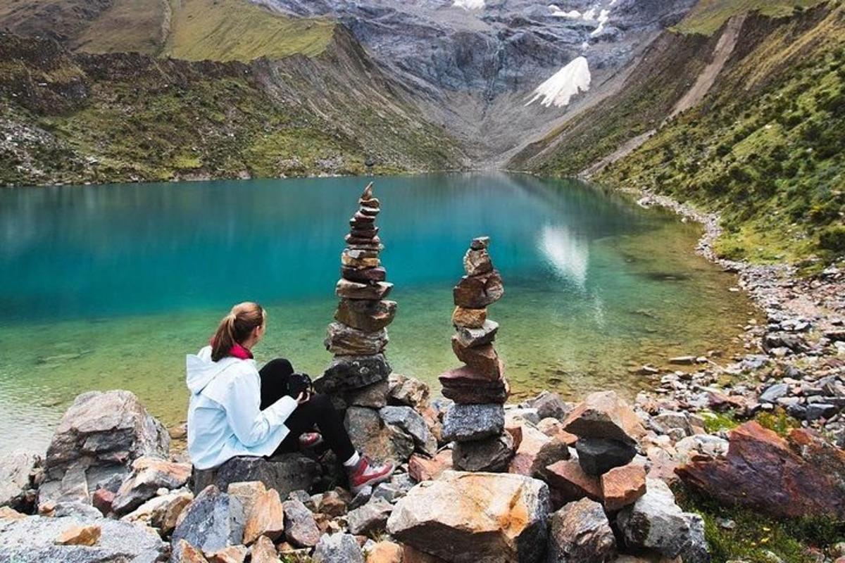 una dona asseguda sobre un munt de roques al costat d'un llac