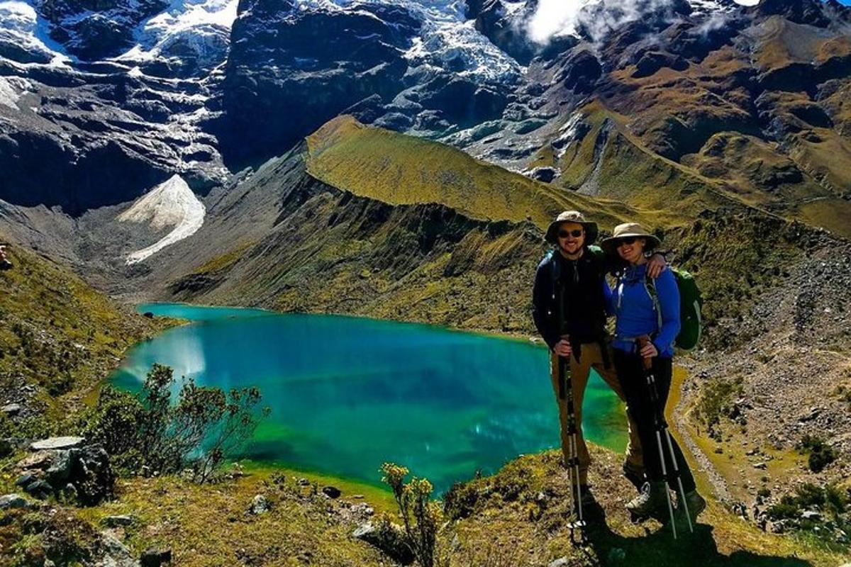 dues persones dempeus al cim d'una muntanya amb un llac