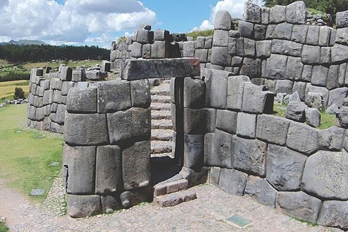 um muro de pedra com uma cruz em um campo