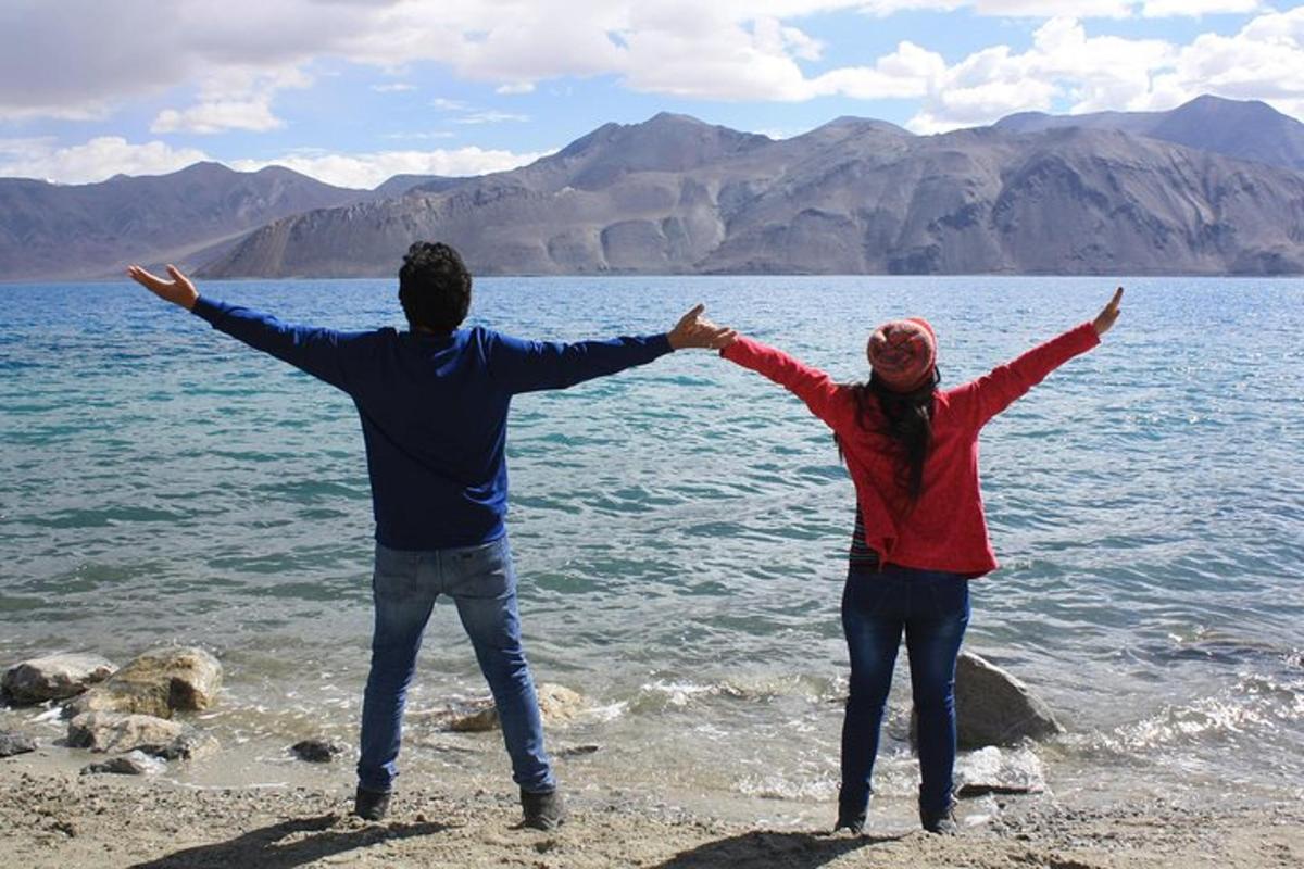 a man and woman standing on the shore of a body of water
