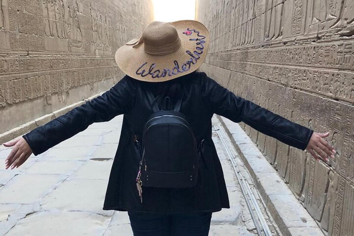 una persona che indossa un cappello di paglia in piedi accanto a un muro
