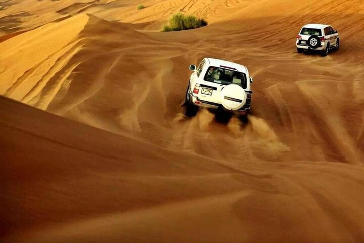 two cars driving in the sand in the desert