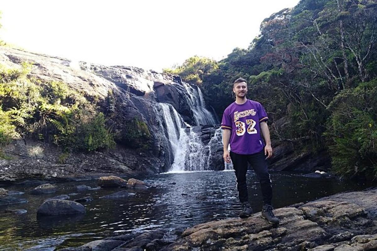 un uomo in piedi su una roccia di fronte a una cascata