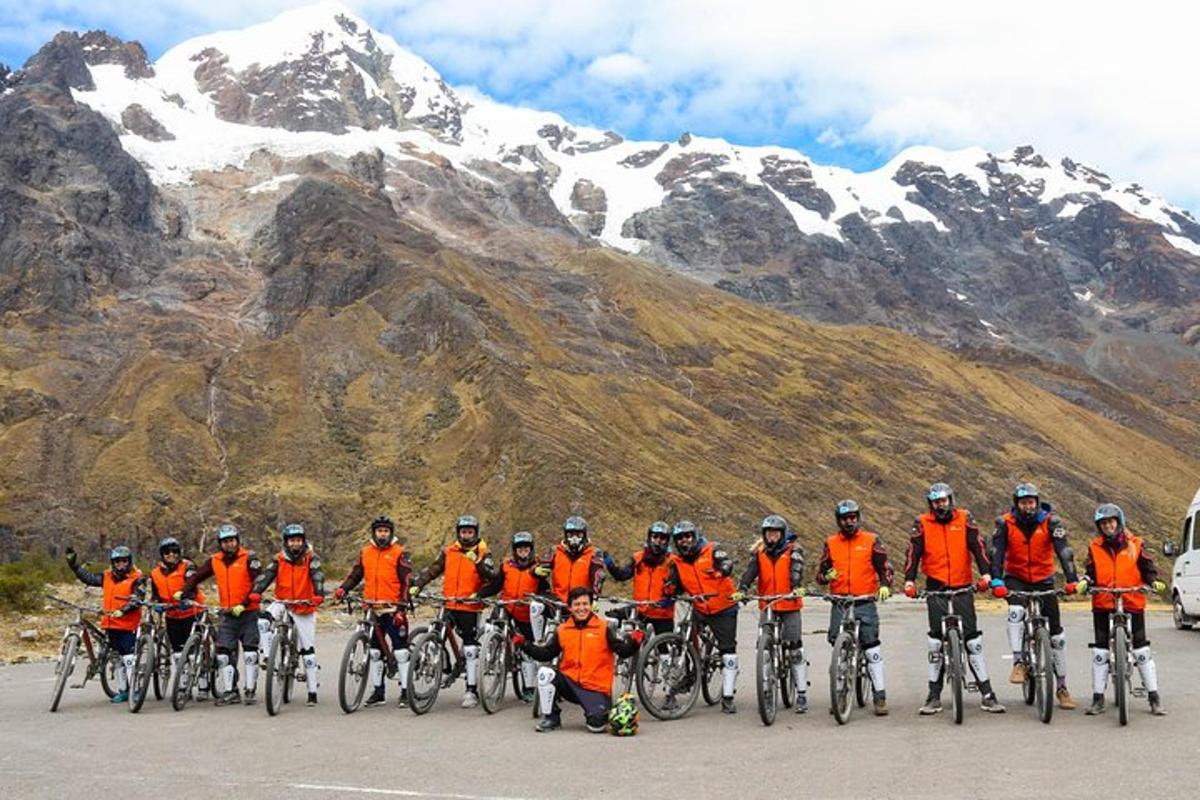 un gruppo di persone con gilet arancioni in bicicletta davanti a una montagna