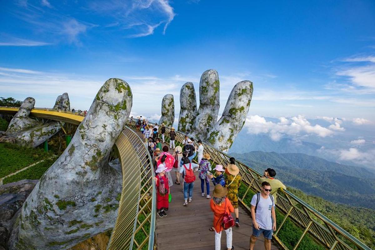 isang grupo ng mga taong naglalakad sa isang suspension bridge na may higanteng kamay