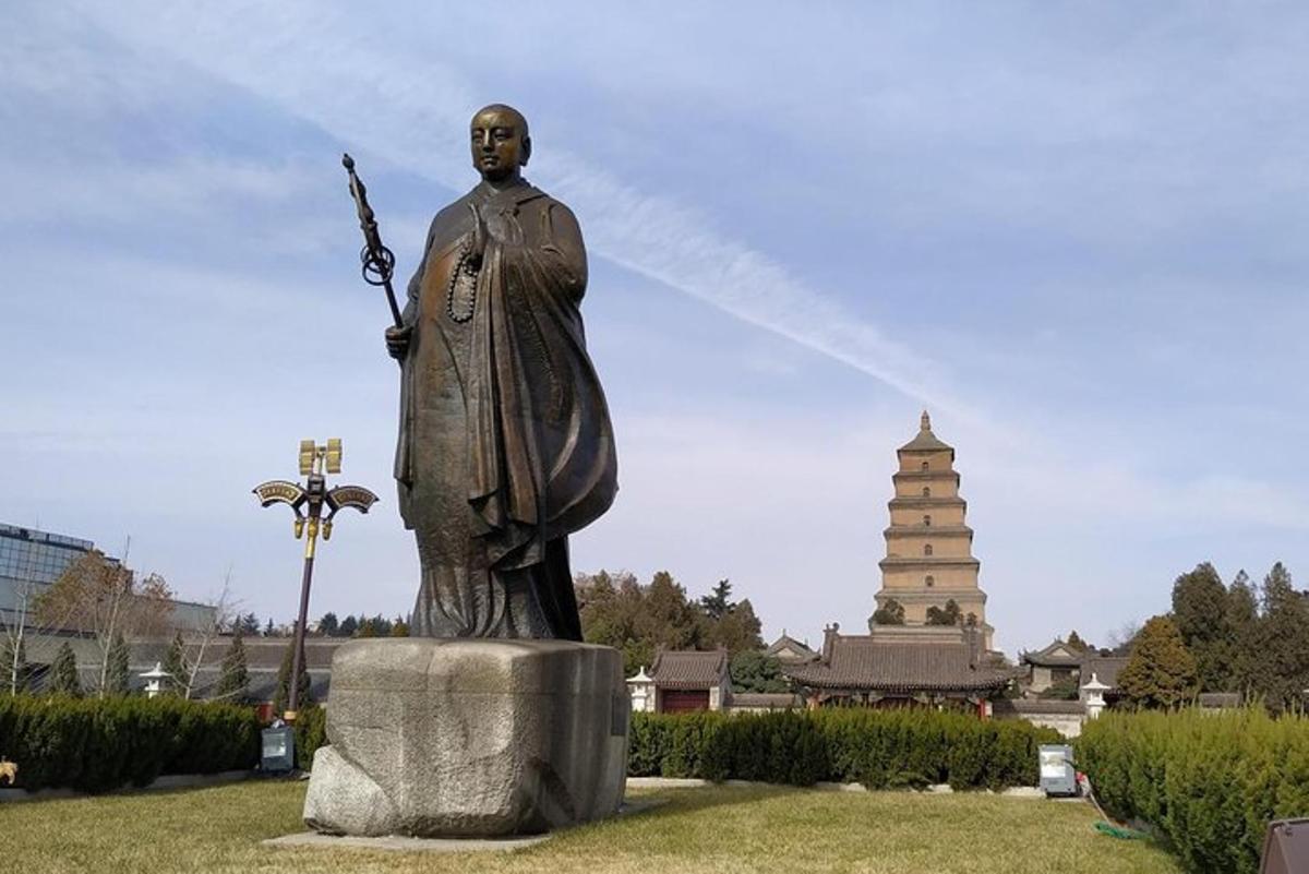 a statue of a man on a rock in front of a pagoda