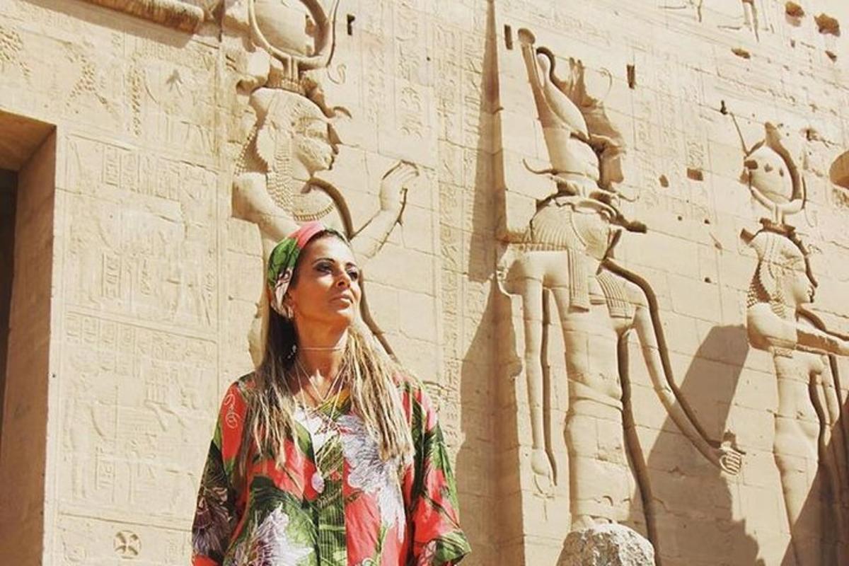 uma mulher em pé em frente a uma parede com uma escultura