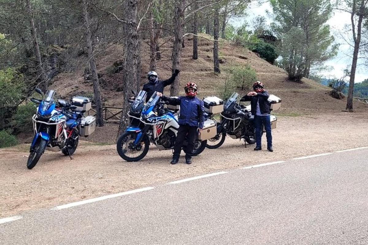un gruppo di persone in piedi accanto a motociclette sul ciglio di una strada