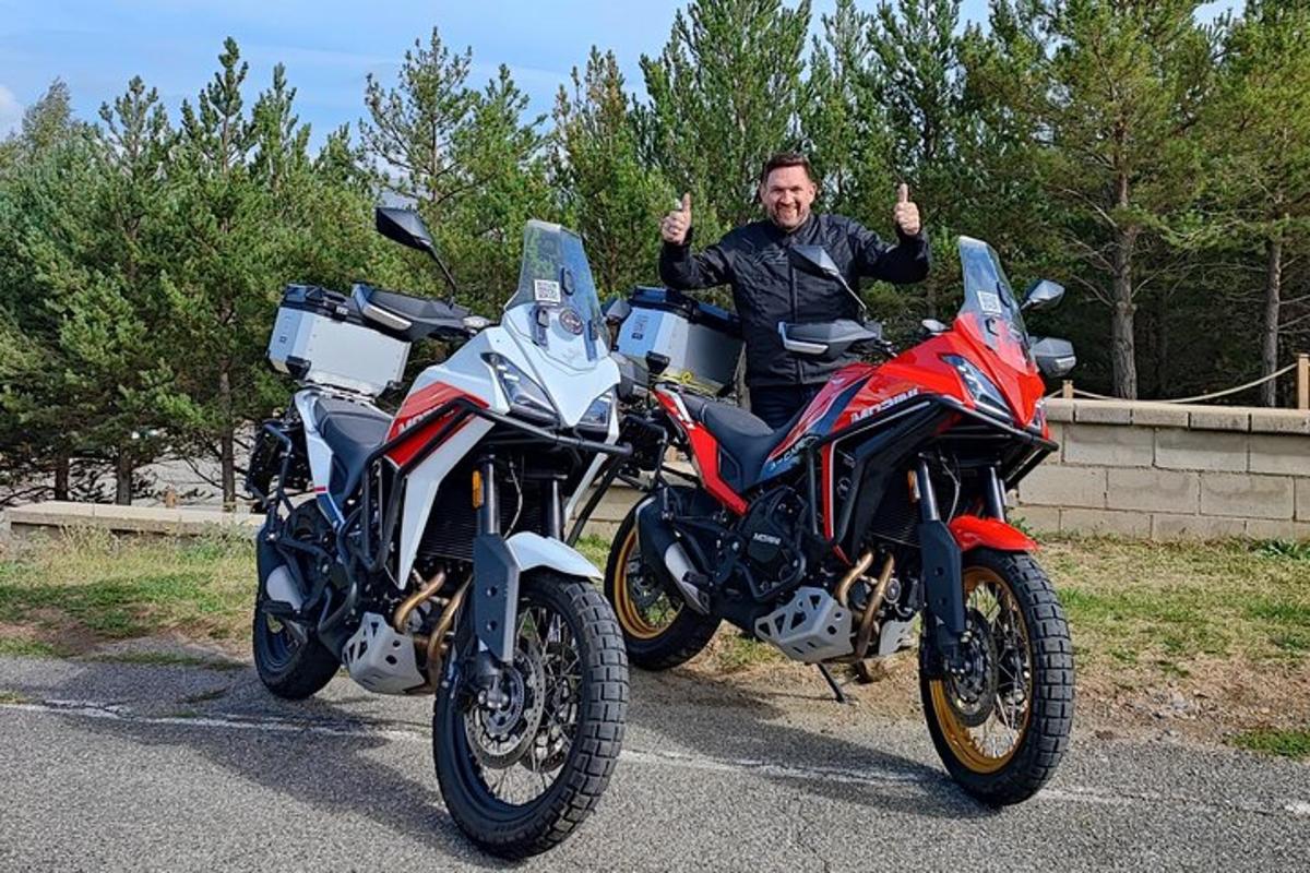 un uomo che fa il gesto del pollice in su accanto a due motociclette