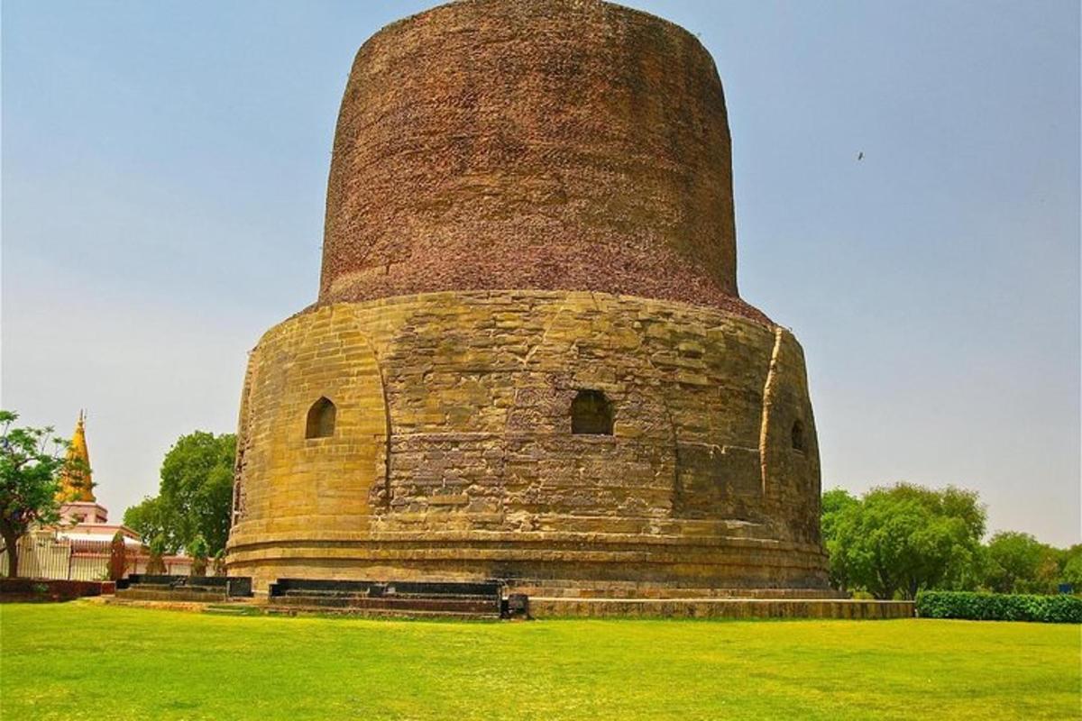 Una gran torre de ladrillo con un banco en un campo.
