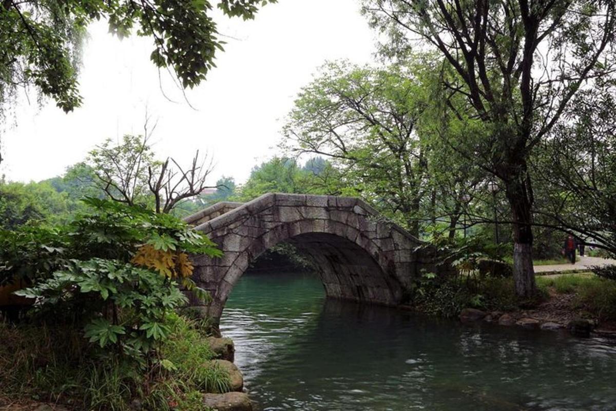 eine Steinbrücke über einen Fluss in einem Park