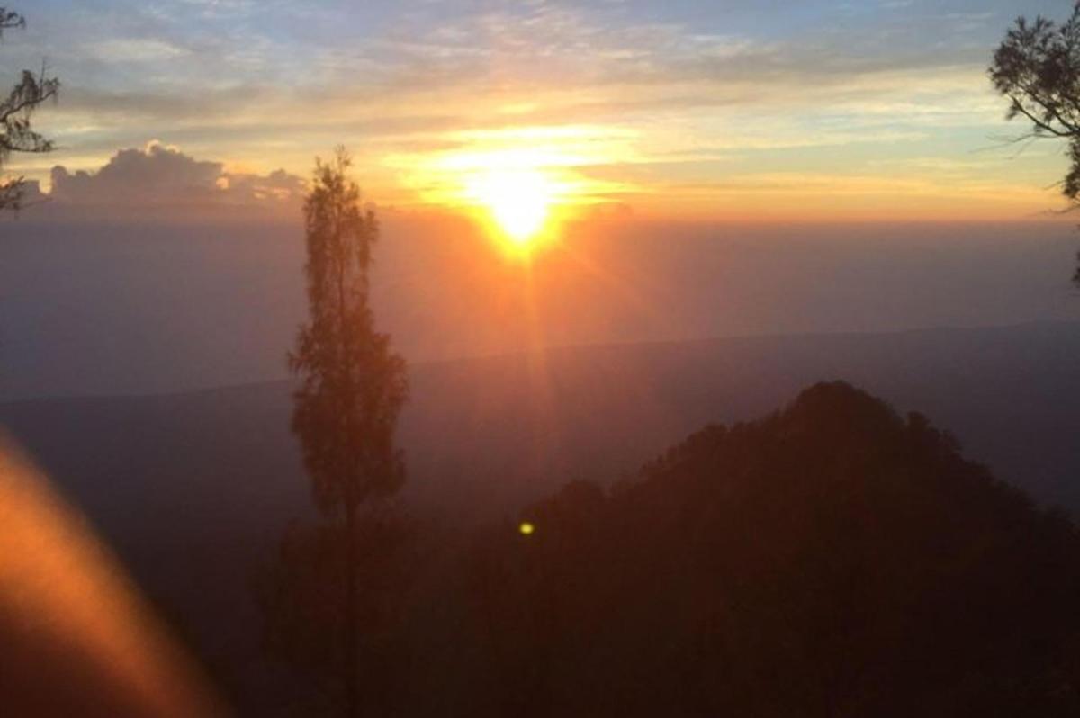 Una puesta de sol con el sol saliendo sobre una montaña