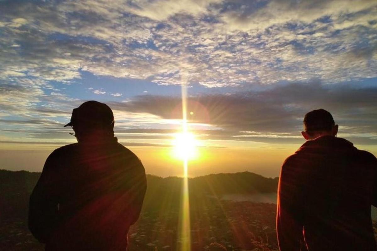 Dos personas de pie frente a una puesta de sol