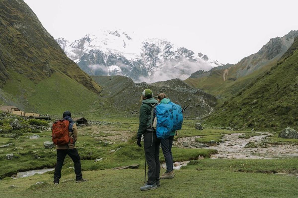 Un grupo de tres personas de pie en la cima de una montaña.