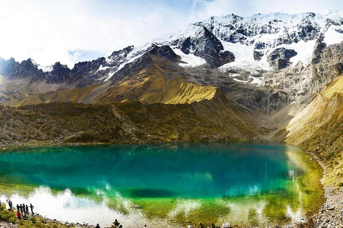 un gruppo di persone in piedi intorno a un lago di montagna