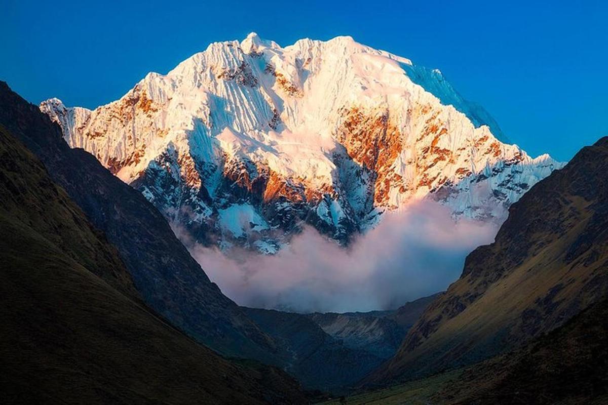 a snow covered mountain with clouds in front of it
