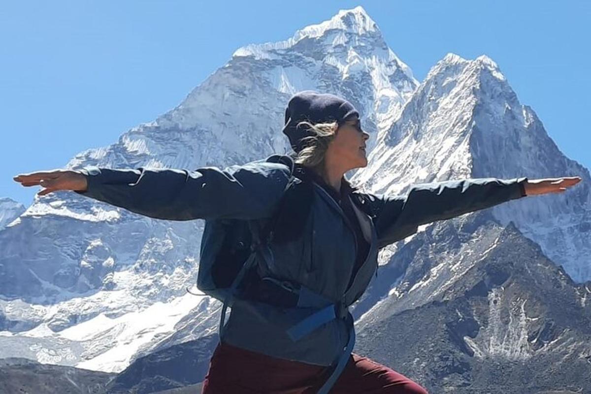 una donna in piedi sulla cima di una montagna con le braccia tese