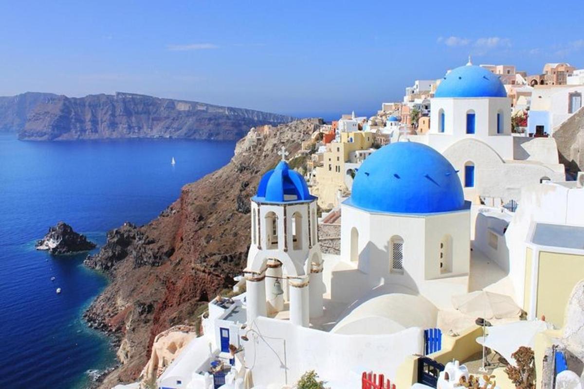 Μια ομάδα λευκών κτιρίων με μπλε θόλους σε έναν απότομο βράχο