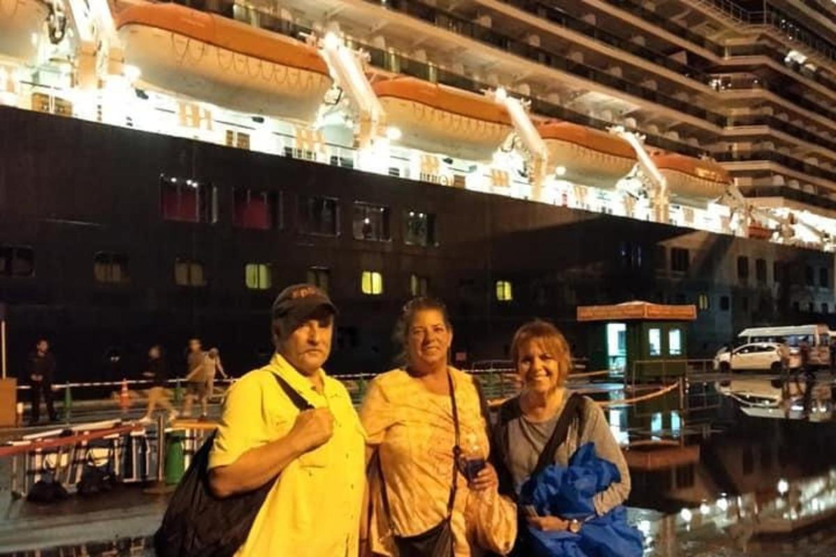 Tres personas de pie frente a un crucero