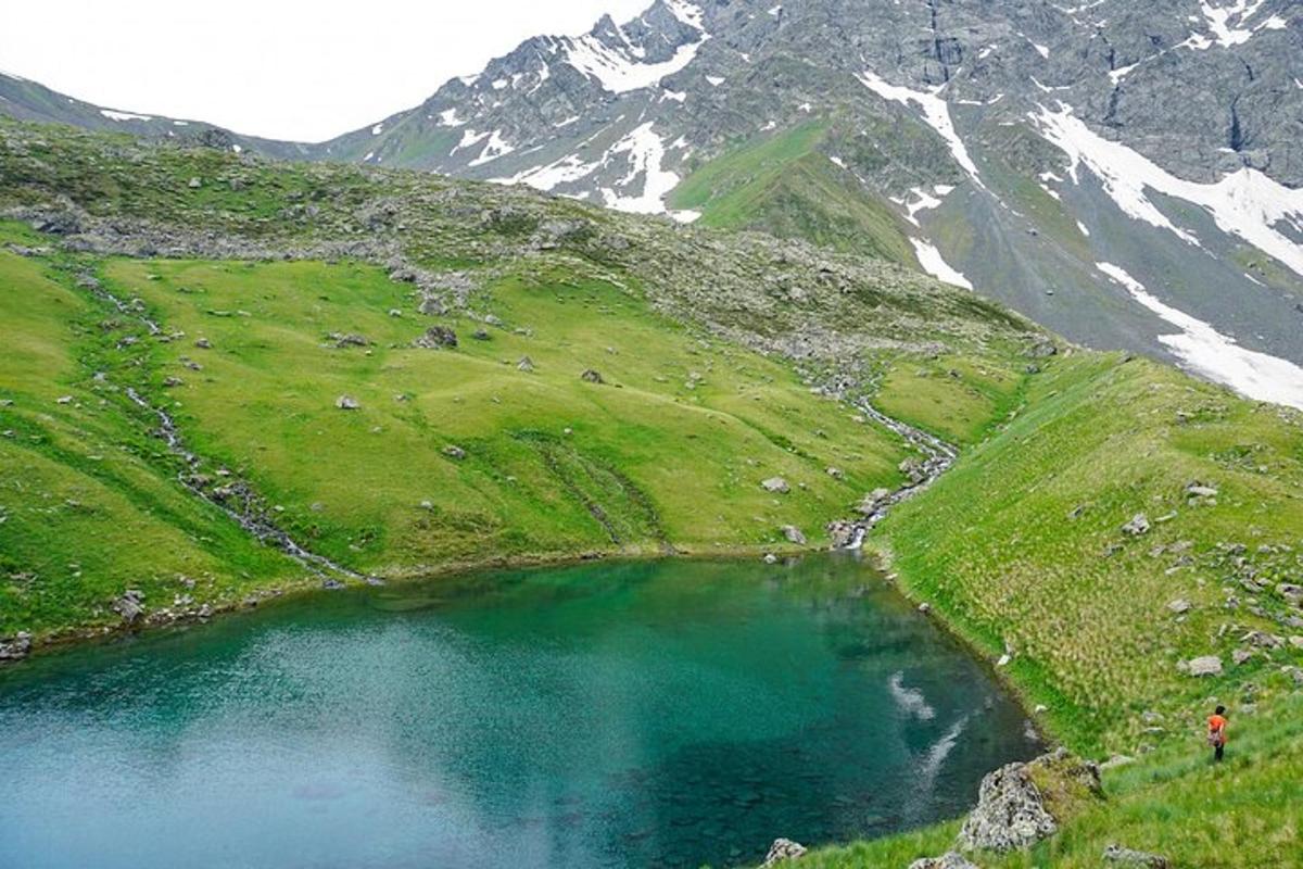 una persona in piedi accanto a un lago su una montagna