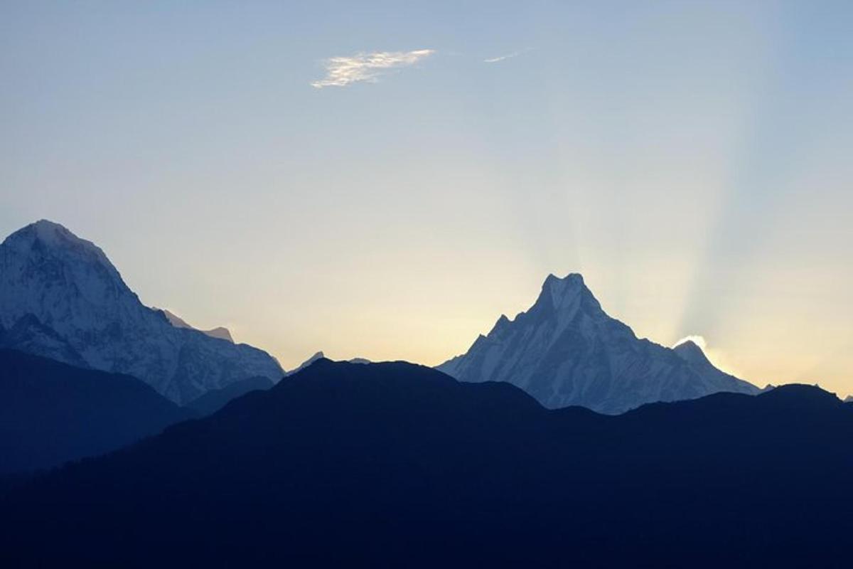 a silhouette of mountains with the sun setting behind them