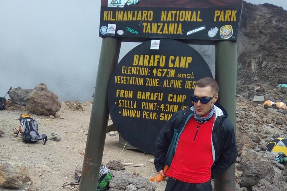 Ein Mann steht vor einem Schild auf einem Berg