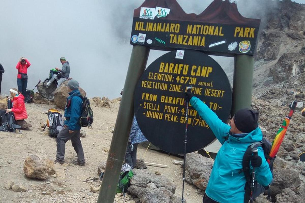 eine Gruppe von Menschen steht neben einem Schild auf einem Berg