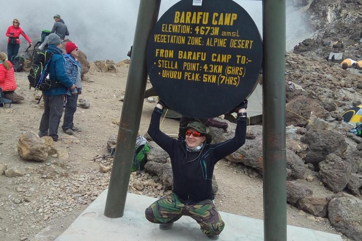 ein Mann hält ein Schild auf einem Berg hoch