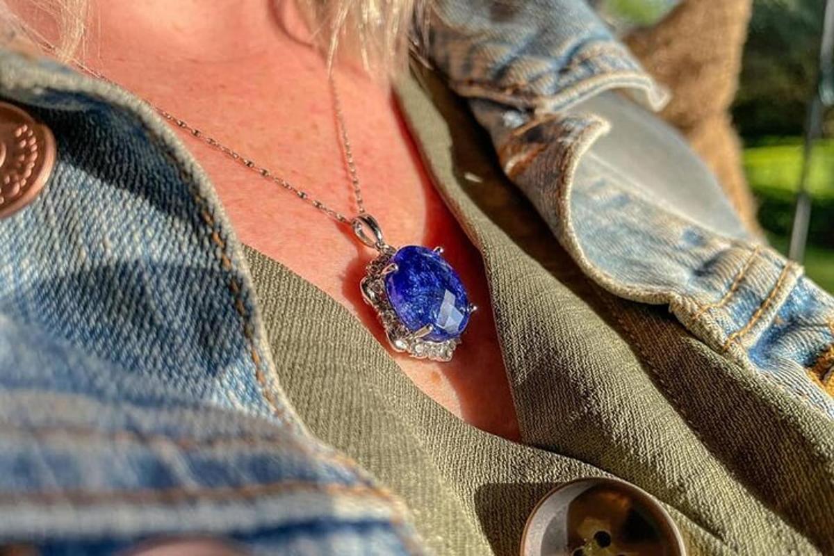 a woman wearing a necklace with a blue stone on her neck